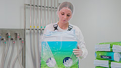 Mitarbeitein in Schutzkleidung und Haarnetz hält SepaFlex® Verpackung in Laborumgebung in der Hand
