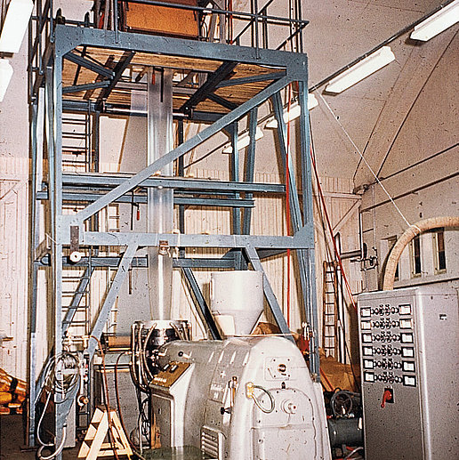 The picture shows the first extruder used at Bischof+Klein for producing plastic packaging in a production hall. 