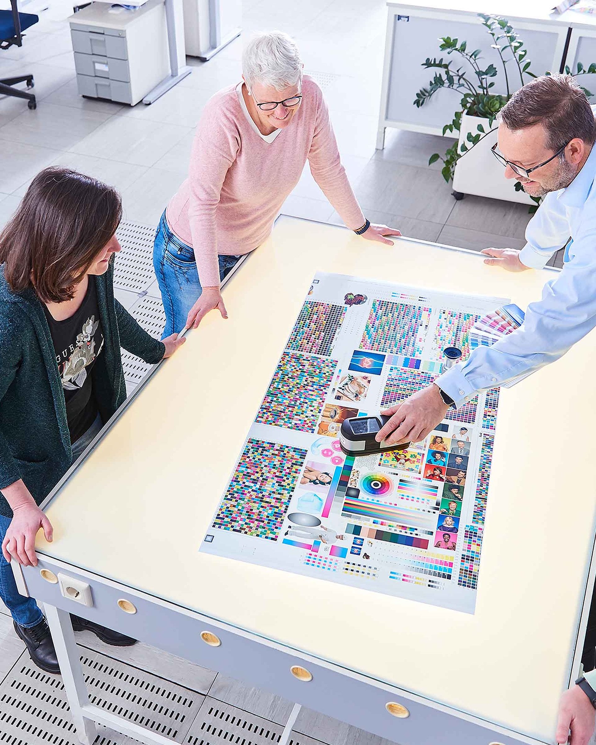 Quatre collaborateurs sont réunis autour d'une table et discutent d'un échantillon d'impression.