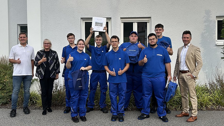 Seven new trainees in Konzell with training manager Wolfgang Schollerer and plant manager Armin Kienberger. The trainees are wearing blue Bischof+Klein T-shirts and blue work pants