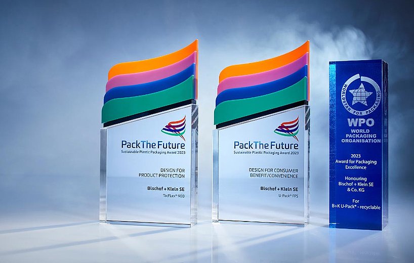 Zdjęcie z trzema nagrodami zdobytymi w 2023 roku: World Star Packaging Award dla opakowania U-Pack® nadającego się do recyklingu, Pack The Future Award dla opakowania U-Pack® ffs oraz Pack The Future Award dla opakowania TacFlex® 900. Nagrody stoją obok siebie na ciemnym tle i są podświetlone.