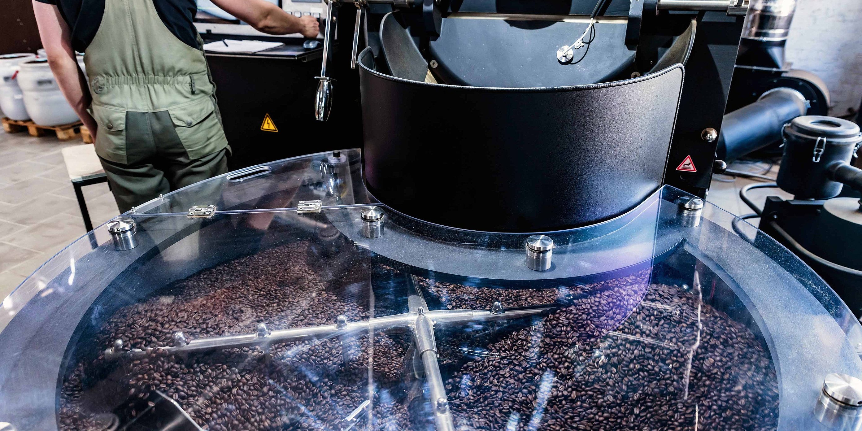 Coffee roasting machine with freshly roasted coffee beans and a person in the background