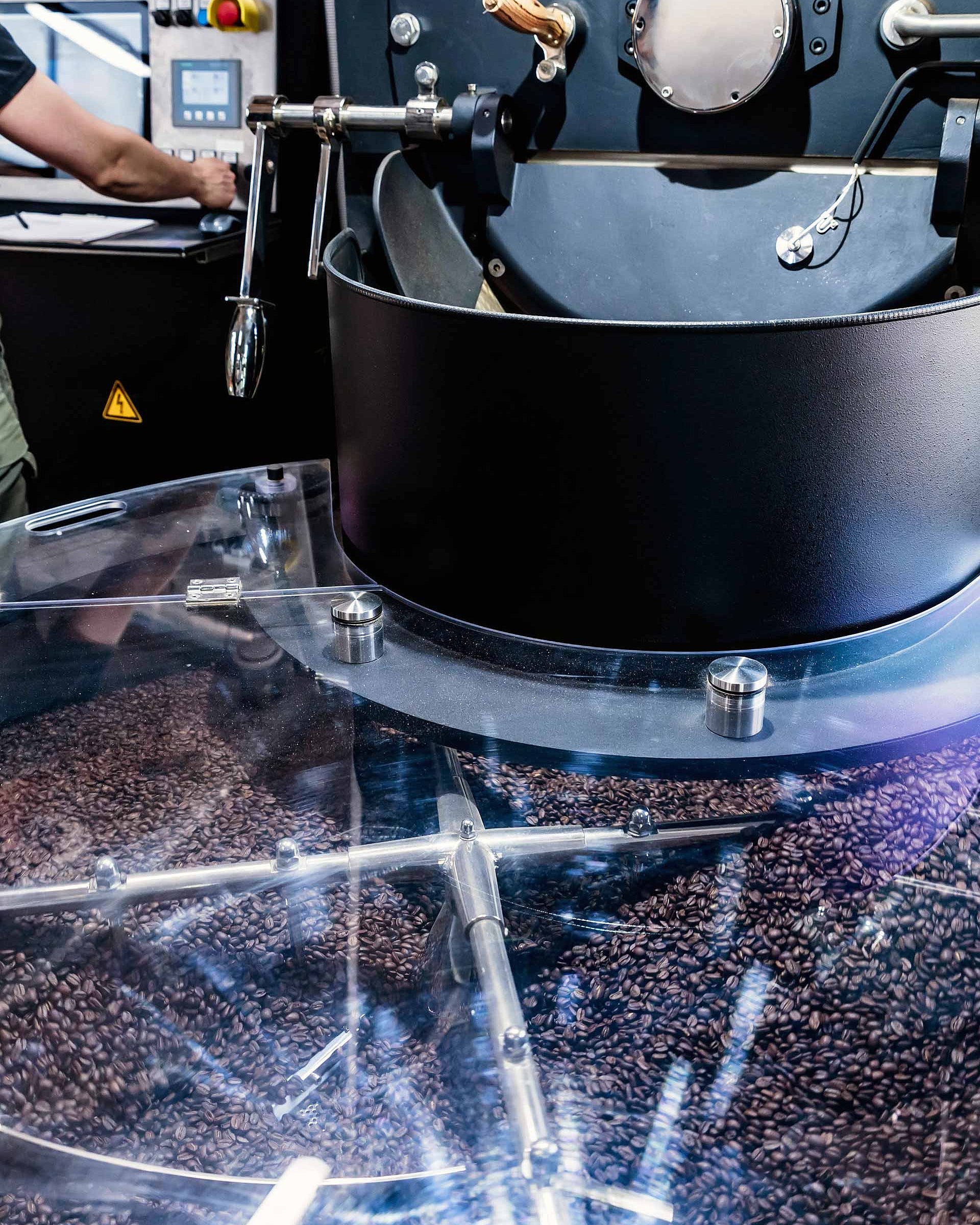 Coffee roasting machine with freshly roasted coffee beans and a person in the background