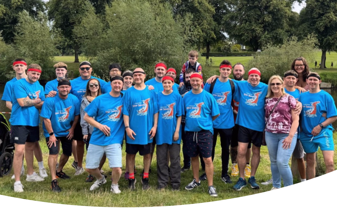 Einige Kollegen von unserem Standort in der UK. Sie tragen ein blaues T-Shirt mit einem Drachenlogo. Das Foto ist nach dem Bootsrennen entstanden