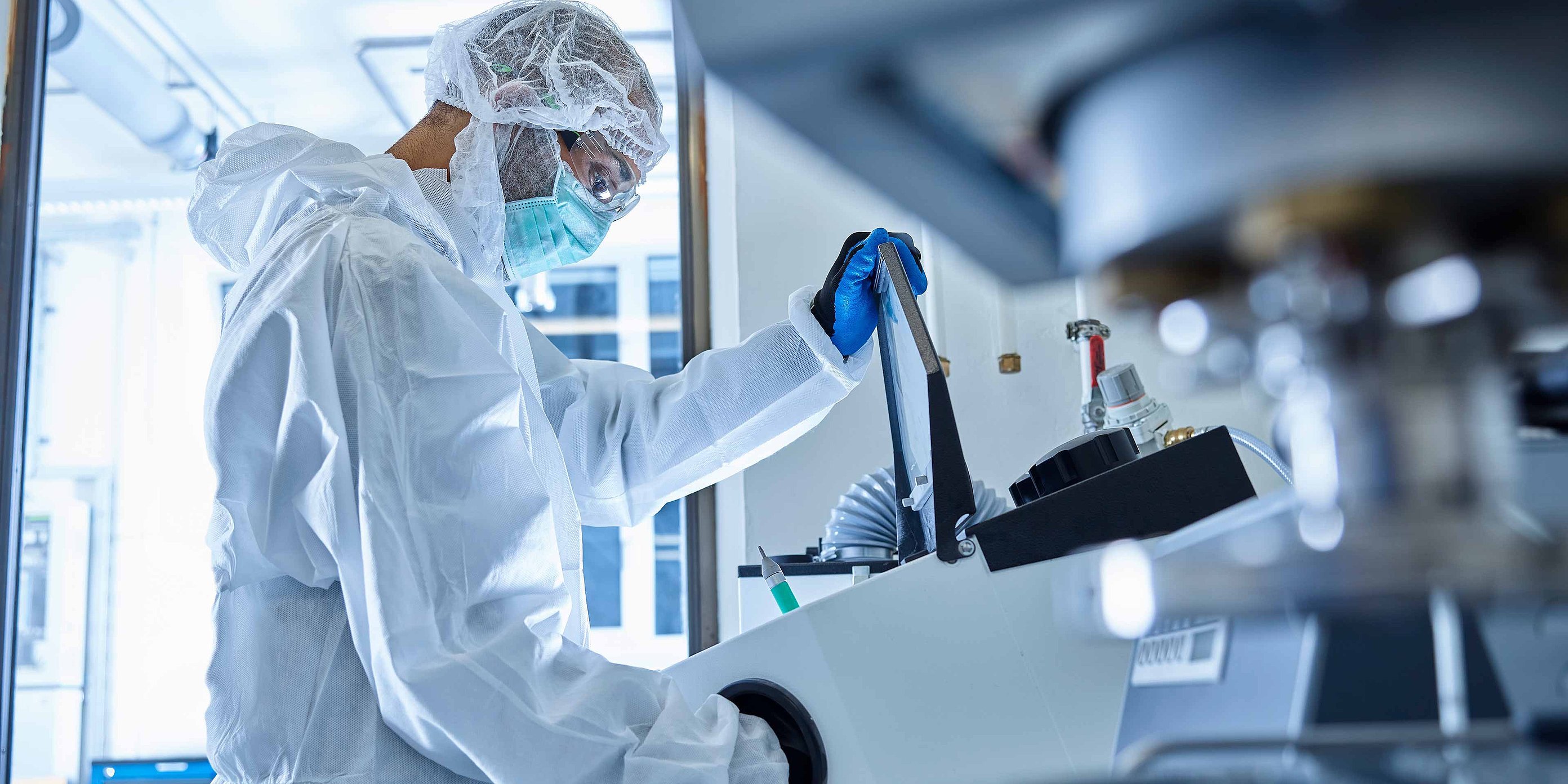 Person in Schutzkleidung bedient Laborgerät in Laborumfeld
