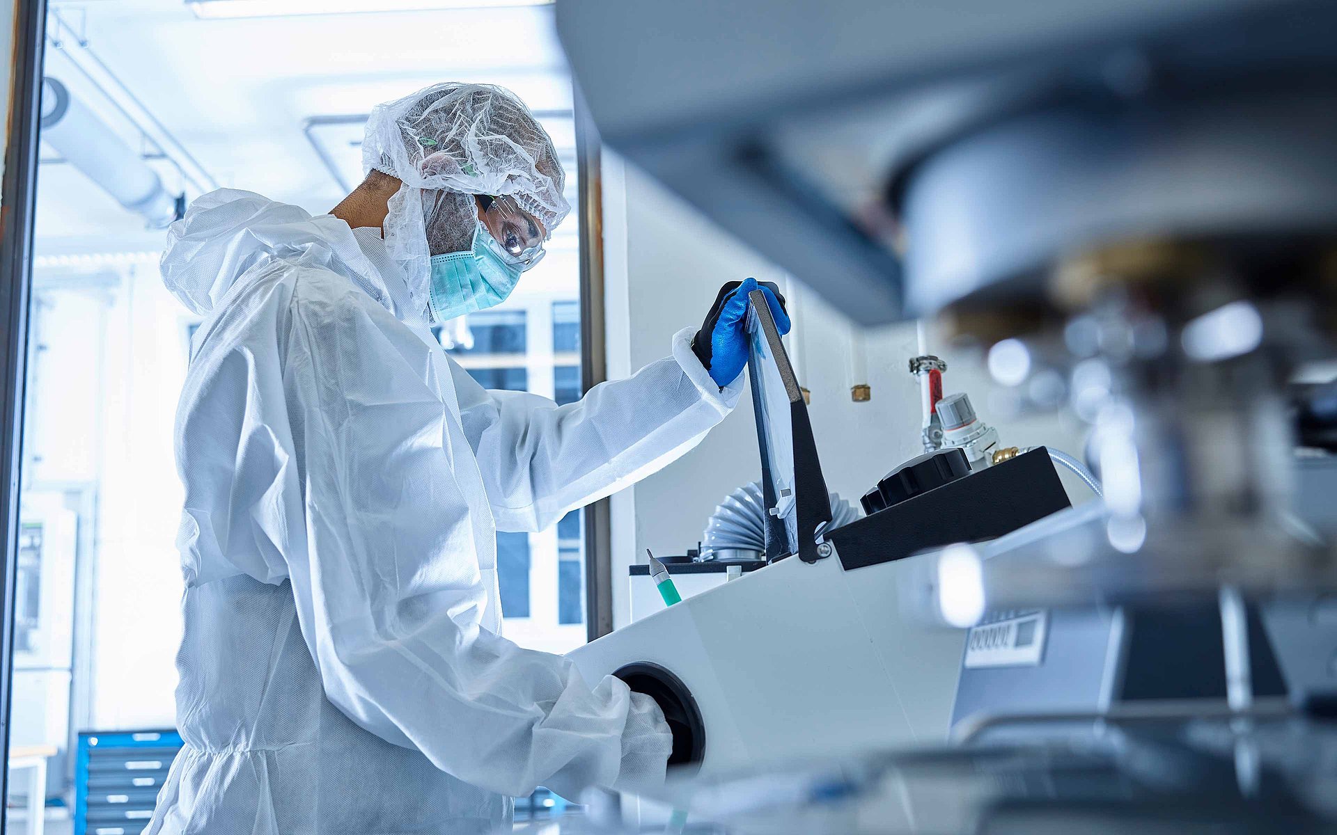 Osoba w odzieży ochronnej obsługuje sprzęt laboratoryjny w środowisku laboratoryjnym