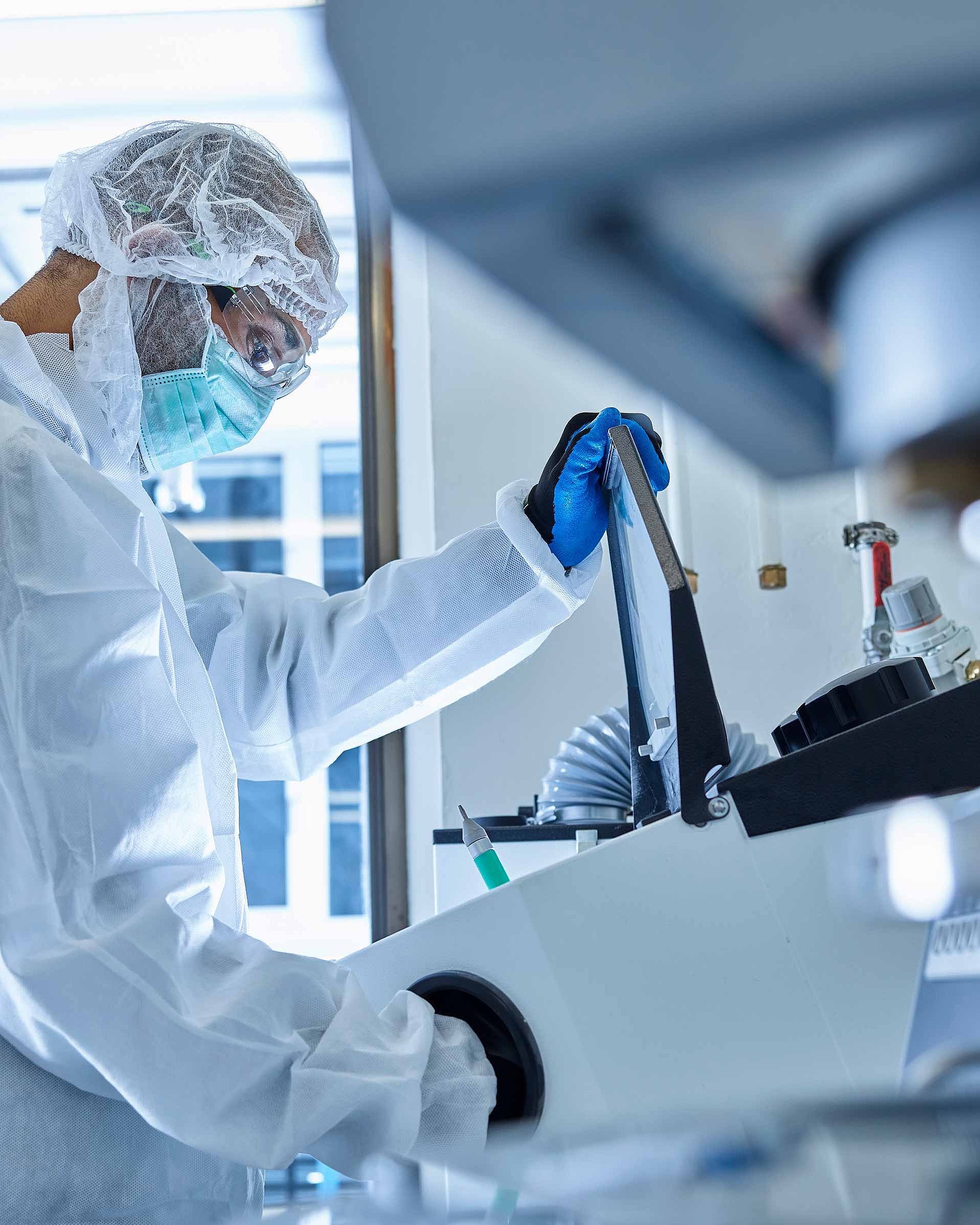 Person in Schutzkleidung bedient Laborgerät in Laborumfeld