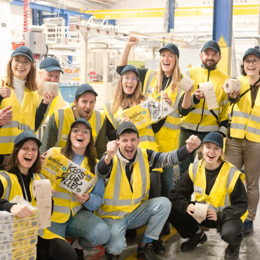  Bischof+Klein Mitarbeiterin zusammen mit Mitarbeitenden von Wildplastic, Goldeimer und Wepa in der Produktionshalle. Sie halten alle einen Toilettenpapierpackung von Goldeimer in der Hand